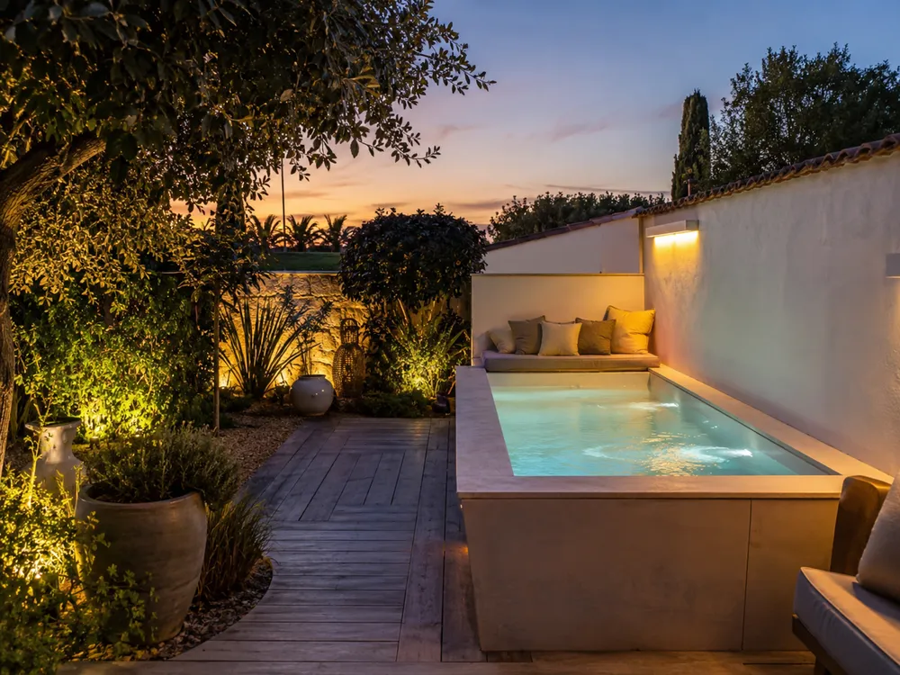 Petite piscine élégante éclairée en soirée dans un jardin compact